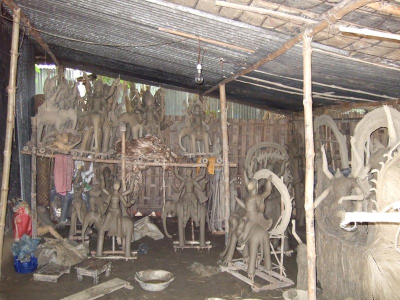 lots of clay sculptures in a hut waiting to be painted and prepared for Durga Puja

