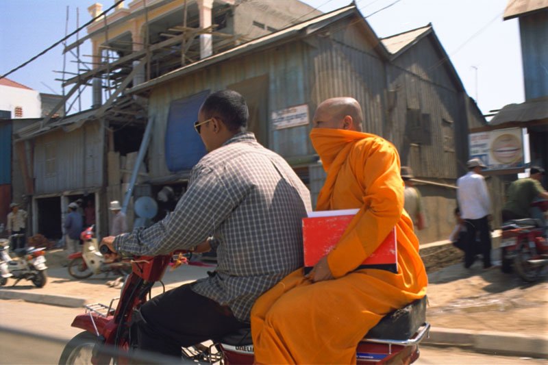 a monk getting a ride on the back of a motorbike
