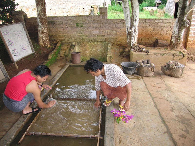 making "Shan paper" from the bark of the mulberry tree.  they mix it with ash & lime, boil & pound it. here they've spread the fibre on a tray with water & are stirring it; they'll place petals & leaves for decoration
