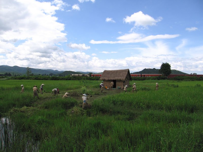 men working in the hilly plateau while a train passes by
