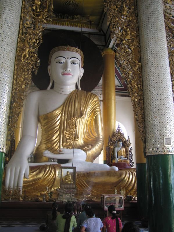 this woman is fanning the Buddha for merit (see the long string she's pulling that moves the fan over the buddha's head)

