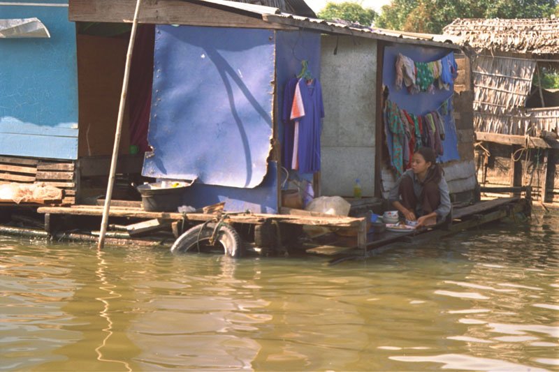 a girl living in one the floating houses, washing dishes
