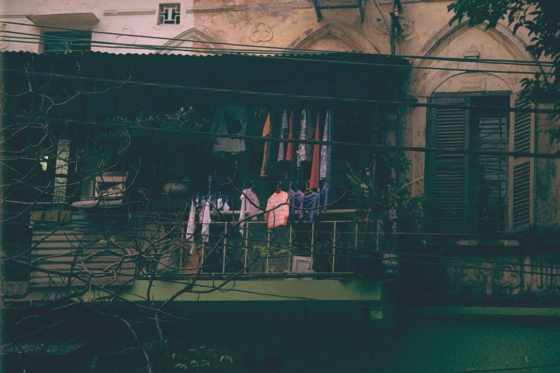 more old wooden shutters and balconies overhanging the street with clothes drying
